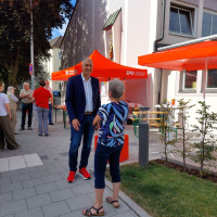 MdB Christoph Schmid im Gespräch mit einer Bürgerin, im Hintergrund der Infostand der Dialogtour.